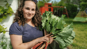Frau mit Rhabarber Ernte in der Hand im Garten