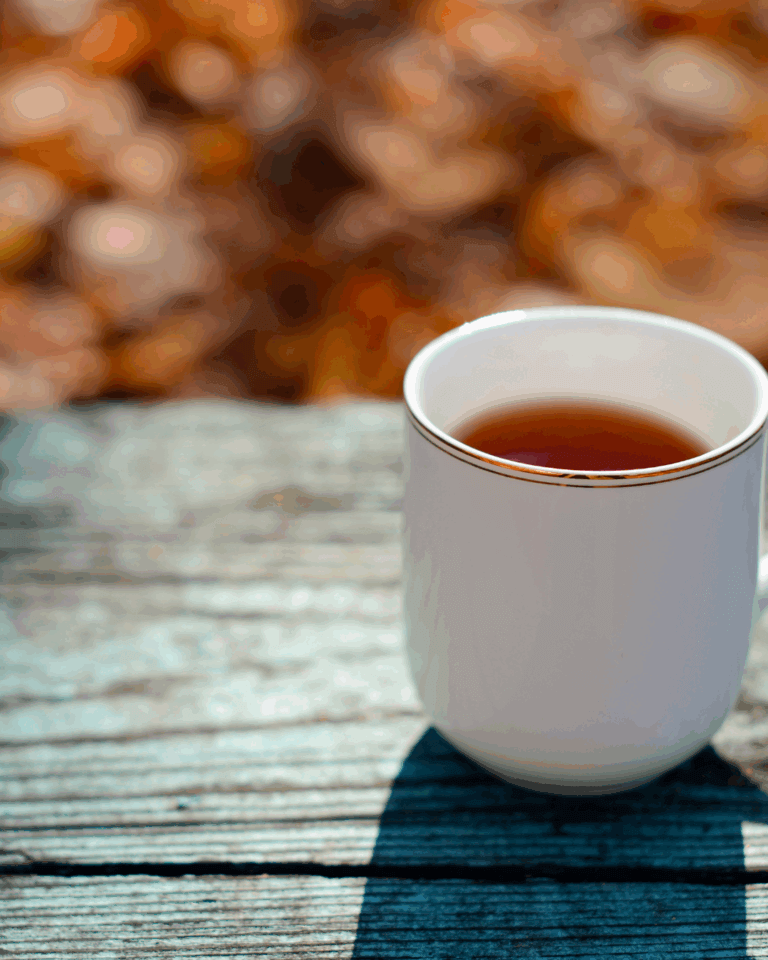 Teetasse auf Holzbank, Herbst